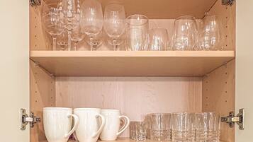 Una cocina con estantes de madera que sostienen diferentes vasos y tazas.