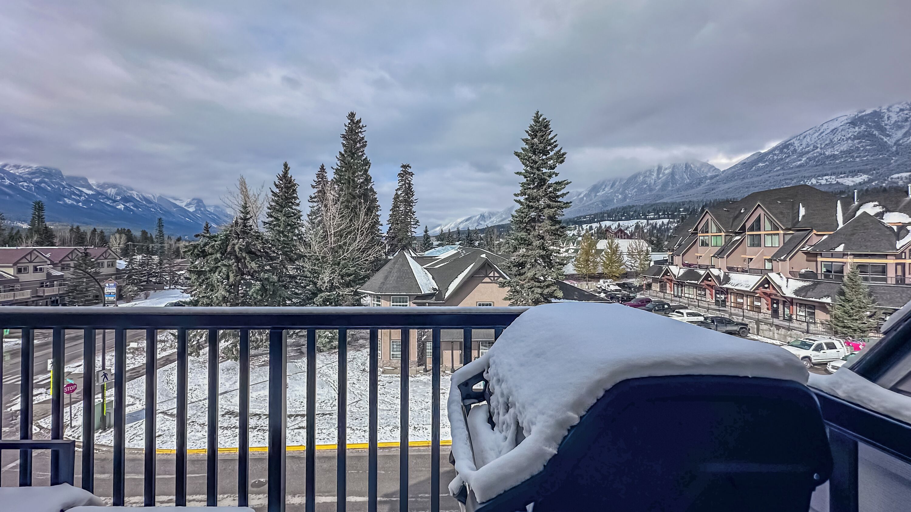 A balcony with a view of a snow-covered town, mountains, and a clear sky.