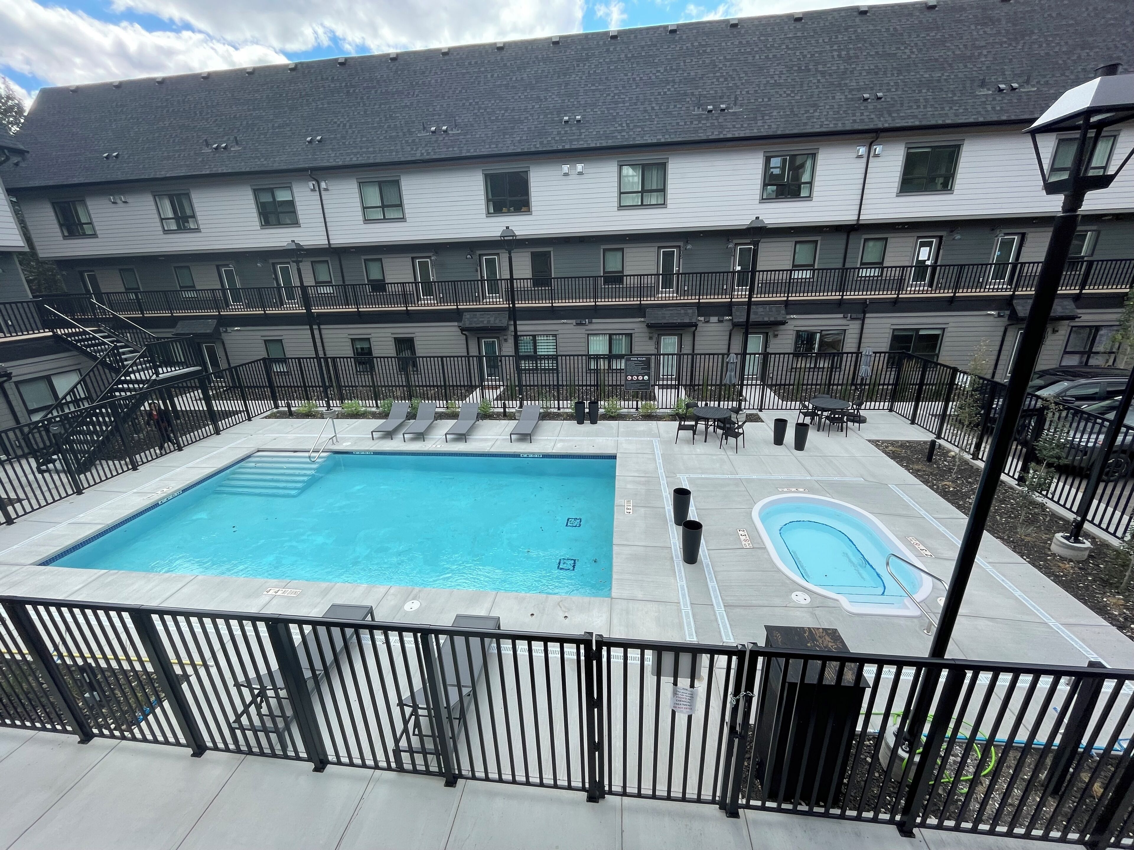 A multi-story building with a rooftop pool area, including two swimming pools and lounge chairs.