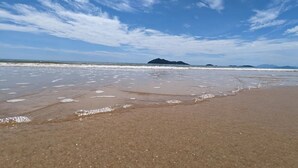 Ein Strand mit blauem Himmel und sanften Wellen.