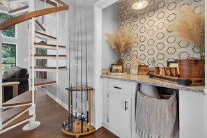 Een moderne keuken met een backsplash van hexagontegels, een houten trap en een eetruimte met uitzicht.
