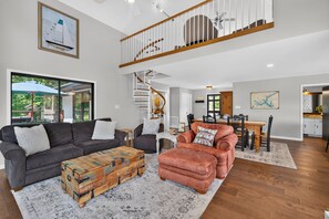 A spacious living area with a large window, a staircase, and a dining area. - Lakeshore Retreat- Lake Sinclair/Milledgeville (Milledgeville)