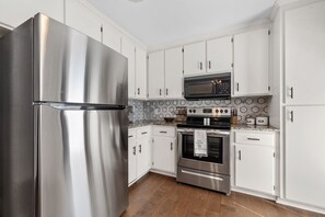 Een moderne keuken met roestvrijstalen apparatuur, witte keukenkastjes en een backsplash van hexagontegels.