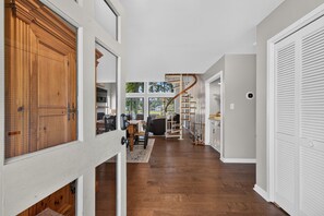 A spacious hallway with a wooden floor, a spiral staircase, and a view of the outdoors.