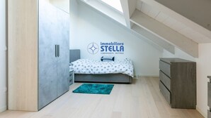 A bedroom with a bed, a wardrobe, a dresser, and a logo on the wall.