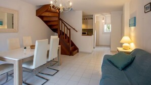 Una sala de estar moderna con una escalera, un comedor y una cocina.