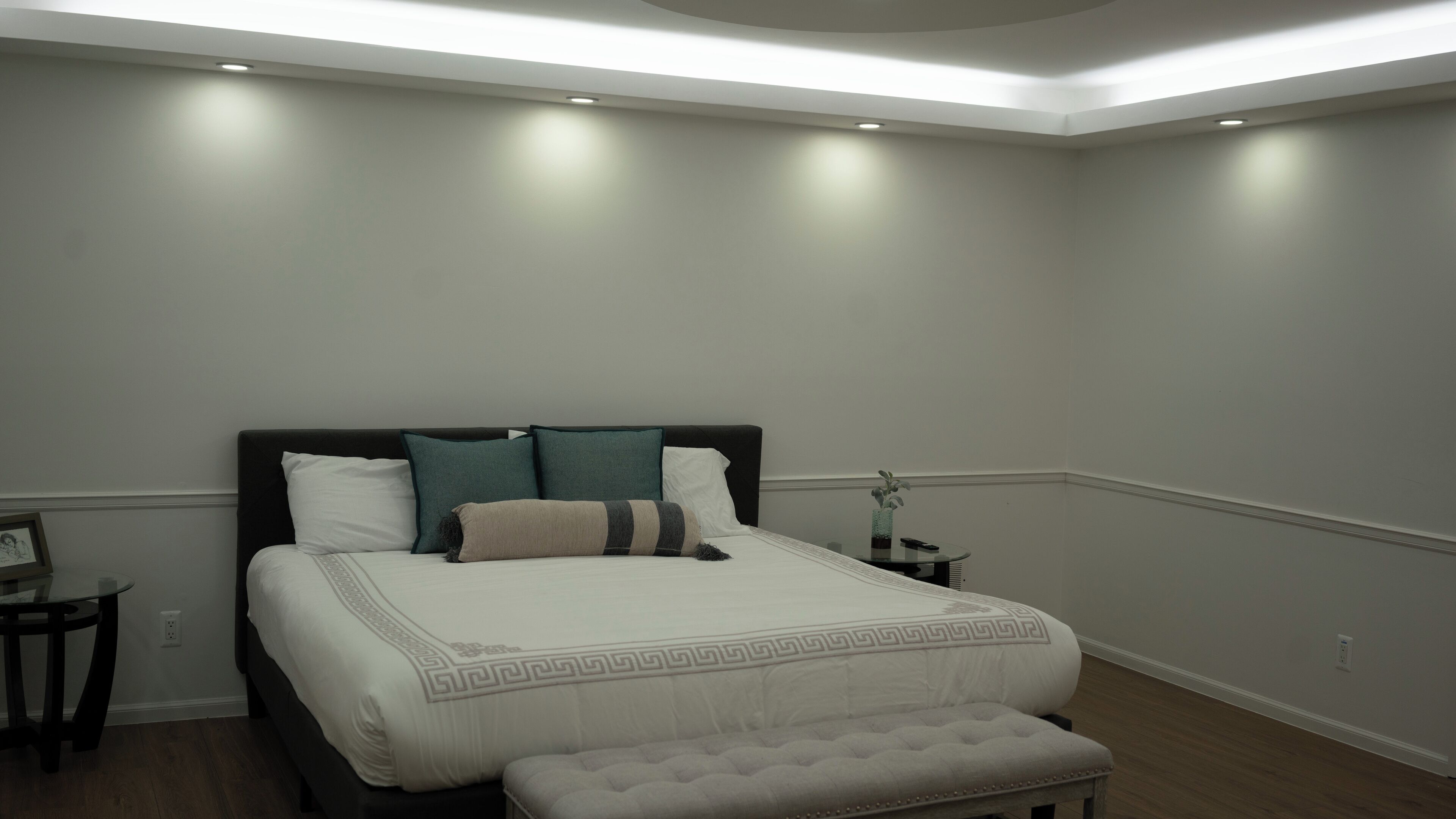 Une chambre à coucher moderne avec un grand lit, des tables de chevet et un banc.