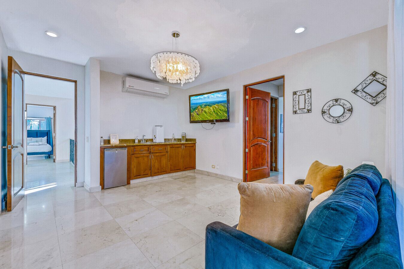 A modern living room with a blue sofa, a wooden cabinet, and a television on the wall.