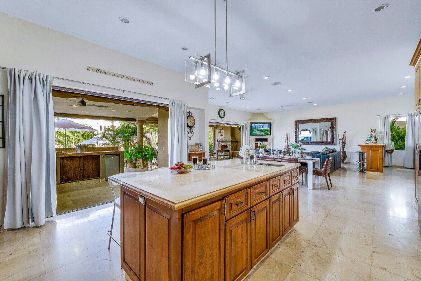 A spacious kitchen with a large island, wooden cabinets, and a dining area with a TV and seating.