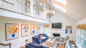 A spacious living room with a high ceiling, a fireplace, and a balcony with white railings. - Relax in Renovated Home w/ Private Plunge Pool; Screened Porch; 2 Master Suites; 4 Min Walk to Beach (Isle of Palms)