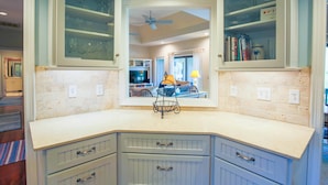 Una cucina con un piano di lavoro bianco, mobili a incasso e una ventola a soffitto.