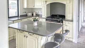 A kitchen with a central island, white cabinetry, a stove, and a window with a view of buildings.