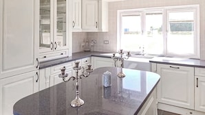 A kitchen with white cabinets, a granite countertop, and a window with a view.