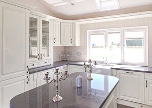 A kitchen with white cabinets, a granite countertop, and a window with a view.