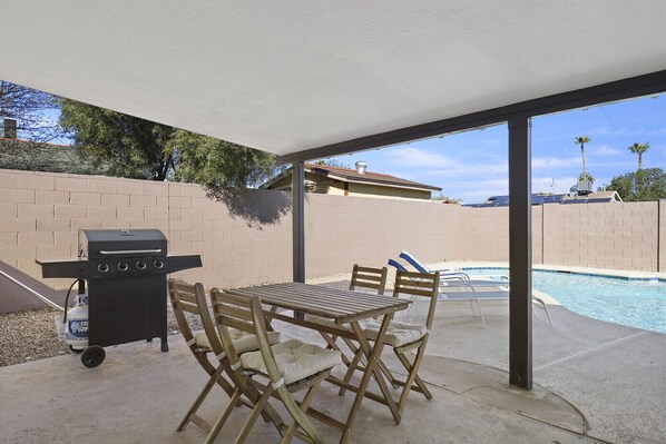Enjoy al fresco dining on the patio, where a barbecue grill and table await, overlooking the pool and surrounding landscape.