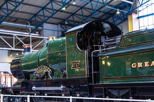 A vintage steam locomotive with the number 3717, displayed indoors with a high ceiling and industrial lighting. - Oak Boutique Lodge (York)