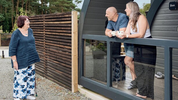 Un bâtiment moderne aux lignes courbes, doté d’une façade en bois et d’une grande baie vitrée.