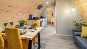 Un intérieur chaleureux, avec des éléments en bois, comprenant un coin repas, une cuisine et un espace salon.