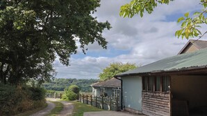 Una propiedad rural con un camino de grava que conduce a un edificio de madera con techo de metal.