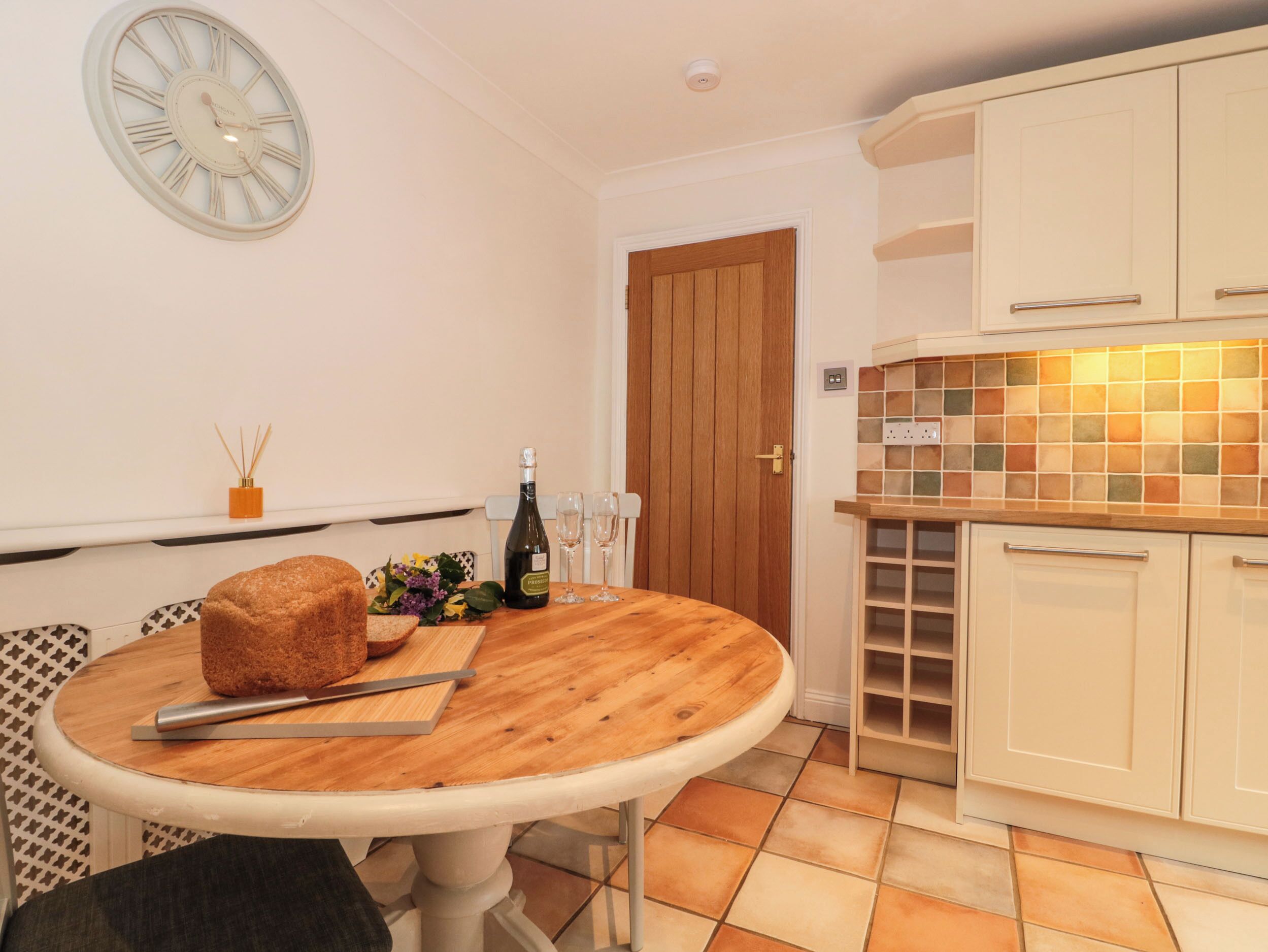 A kitchen with a wooden table, a clock, and cabinets.