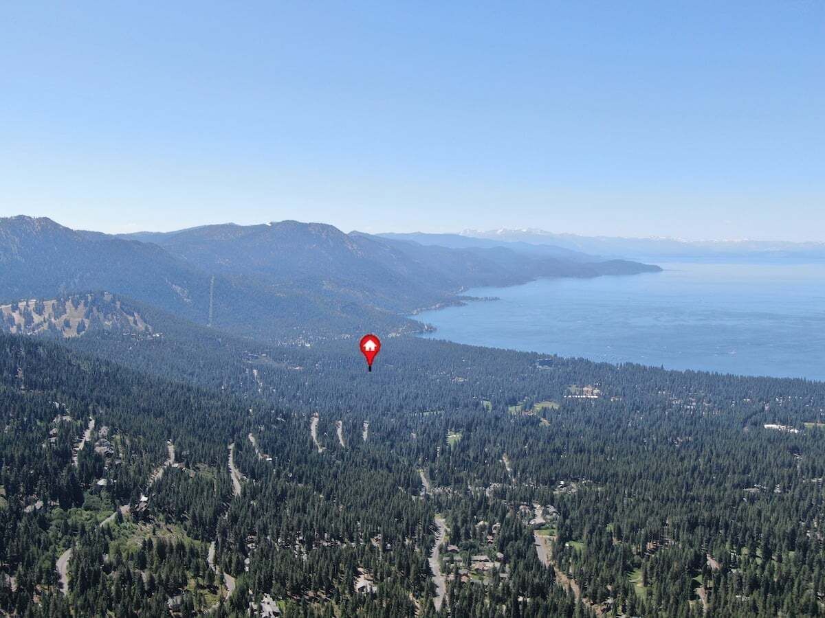 Un paysage montagneux avec une forêt dense, une étendue d’eau et un marqueur de localisation rouge.