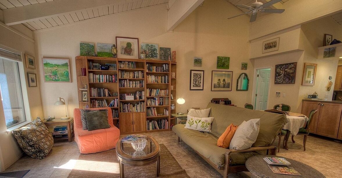 A cozy living room with a sofa, armchairs, a coffee table, and a bookshelf filled with books.