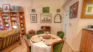 A dining area with a round table set for four, surrounded by green upholstered chairs. A bookshelf filled with books is to the left, and a small side table with a radio is in the center. - Sugar Pine 3 Bedroom Home by RedAwning (Incline Village)