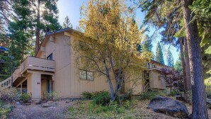 A two-story building with a wooden exterior, a balcony on the upper floor, and a large rock in the foreground. - Sugar Pine 3 Bedroom Home by RedAwning (Incline Village)