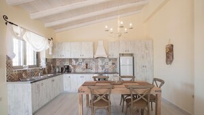Cozinha com mesa e cadeiras de madeira, geladeira e painel de backsplash estampado.