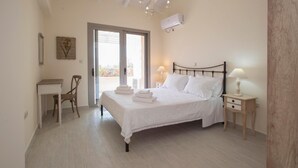 Quarto com cama, mesas de cabeceira, escrivaninha e cadeira. Janela com vista para o exterior.
