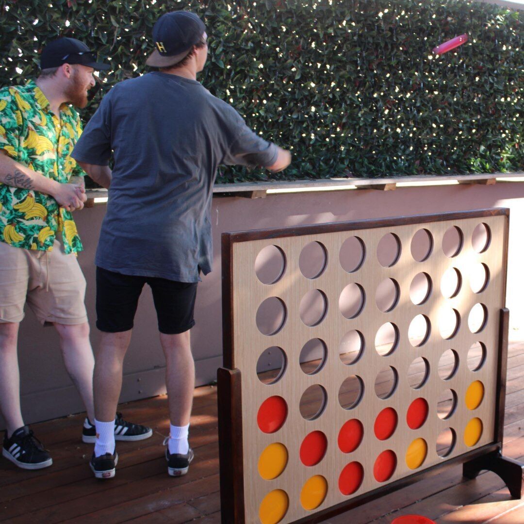 A wooden board game with circular holes, a pink frisbee, and two people standing beside it.