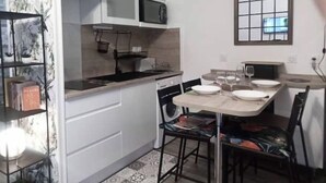A compact kitchen with white cabinets, a microwave, and a dining area with chairs and a table. - nice apartment very well located, covered parking (Lourdes)