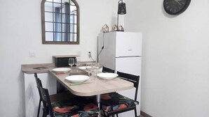 A small dining area with a table set for two, a refrigerator, a clock, and a window with a view. - nice apartment very well located, covered parking (Lourdes)