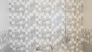 Une salle de bain avec un mur à motifs, des toilettes et une douche.