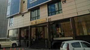 Un moderno edificio de hotel con fachada de vidrio, una entrada visible con escaleras y un letrero que dice "NUVA HOTEL".