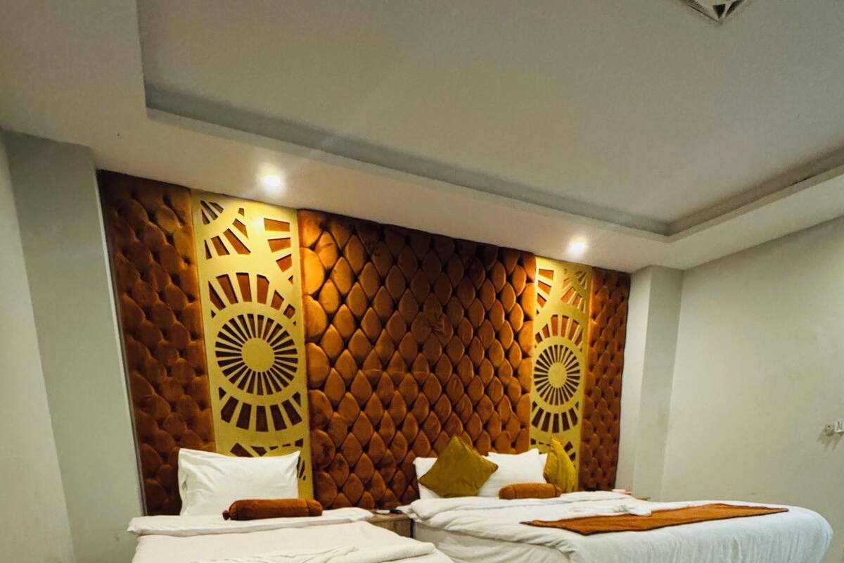 A hotel room with two beds, a wooden headboard, and a red sign on the floor.