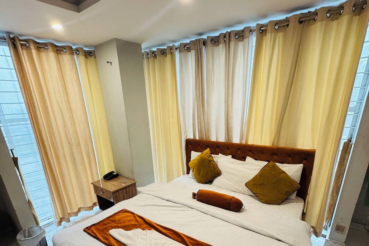A neatly made bed with a brown headboard, white bedding, and two pillows.
