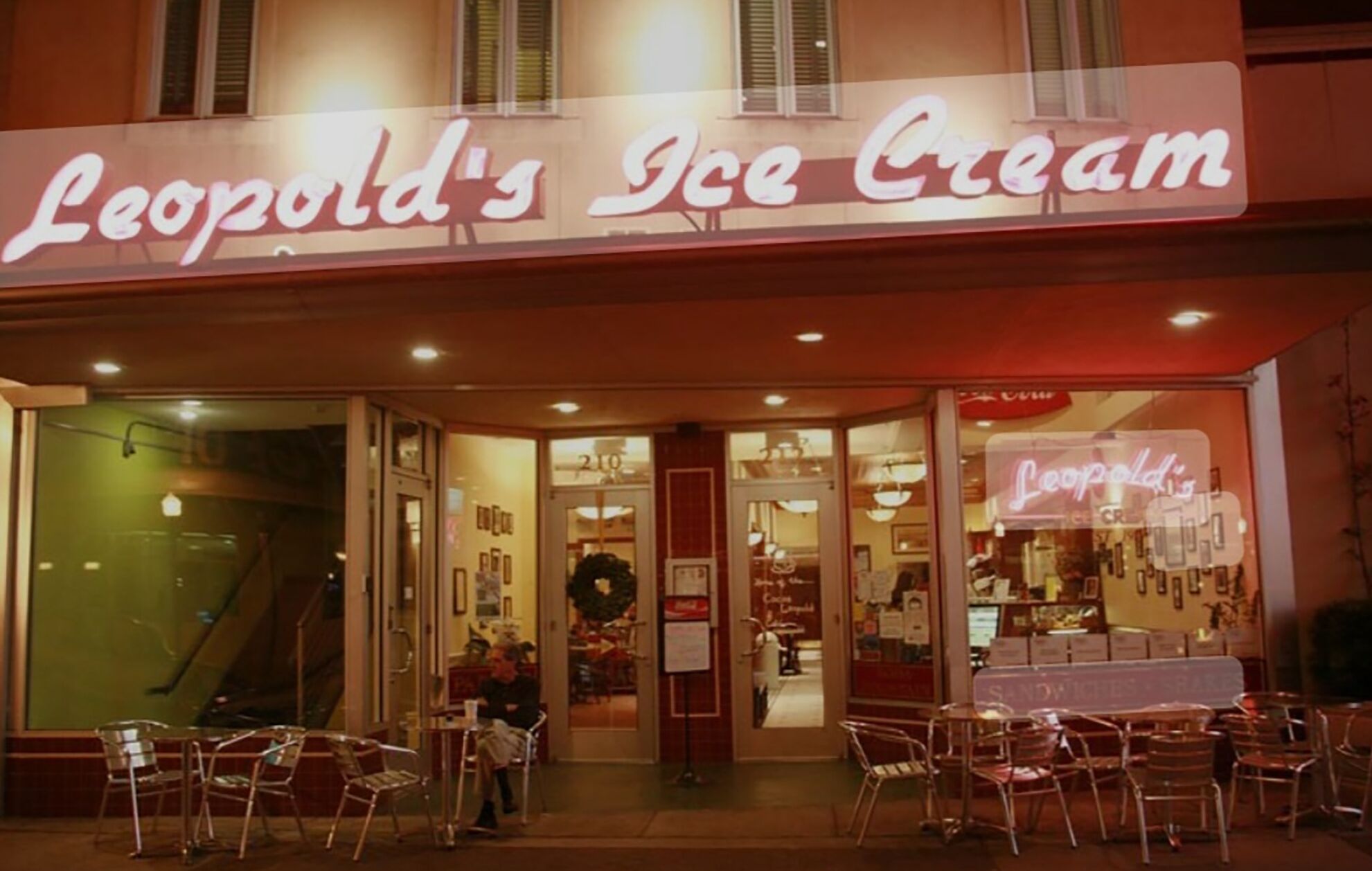 The exterior of Leopold's Ice Cream with a neon sign, glass storefront, and outdoor seating area.