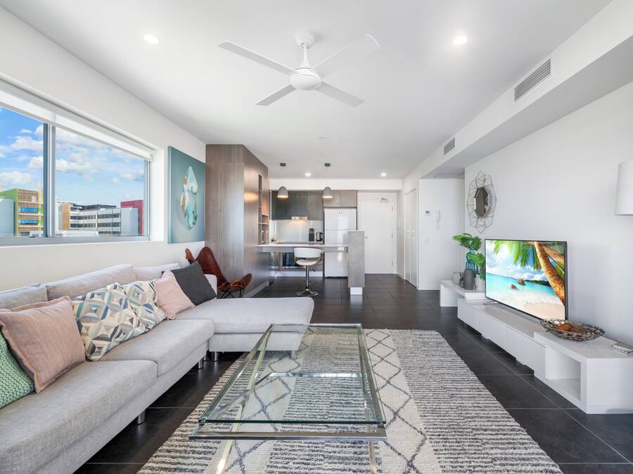 A modern living room with a sofa, TV, and a glass coffee table.