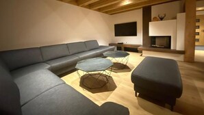 Ein modernes Wohnzimmer mit einer Eckcouch, zwei sechseckigen Couchtischen und einem Kamin.
