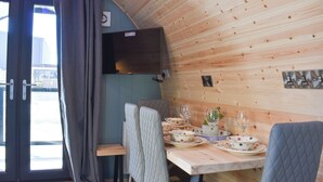 A wooden interior with a dining table set for four, a television mounted on the wall, and a view through a glass door. - 1 bedroom accommodation in Wangford, near Southwold (Wangford, near Southwold)