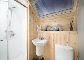 A compact bathroom with a skylight, a sink, a toilet, and a shower.