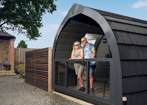 Een modern gebouw met een gebogen dak, een glazen deur, een bakstenen muur en een houten omheining op de achtergrond.