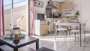 A modern kitchen with white cabinets, a dining area with a table and chairs, and a large window with curtains.
