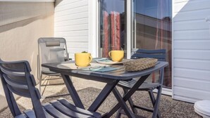 A small outdoor patio with a table and chairs, a sliding glass door, and a white exterior wall.