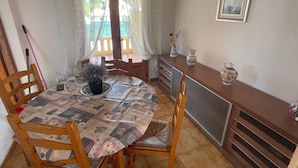 A dining area with a round table covered by a patterned tablecloth, surrounded by wooden chairs. - Quiet private pool villa (Xàbia)
