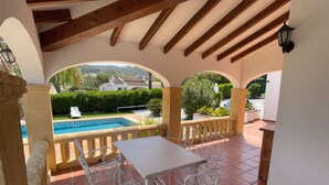 An outdoor patio with a pool, white metal chairs, and a table. - Quiet private pool villa (Xàbia)