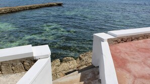 Una escalera que conduce a una costa rocosa con aguas transparentes.