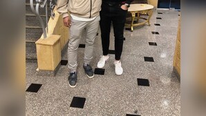 Zwei Personen stehen in einer Lobby mit einer Treppe und einem runden Tisch.