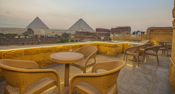 A terrace with wicker furniture and a view of the pyramids. - Life Pyramids Inn (Giza)